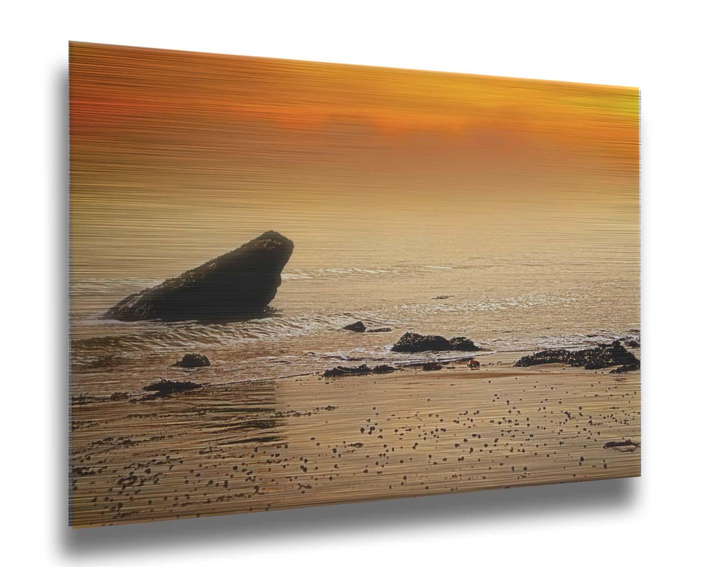 A photo on a beach, looking out at rocks jutting out from the sea against an orange sunset. Printed on metal.