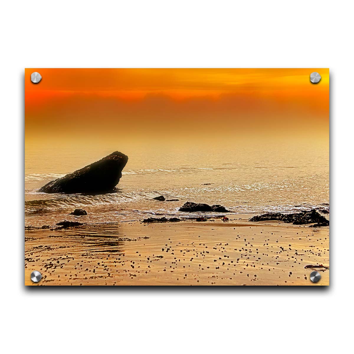 A photo on a beach, looking out at rocks jutting out from the sea against an orange sunset. Printed on acrylic.