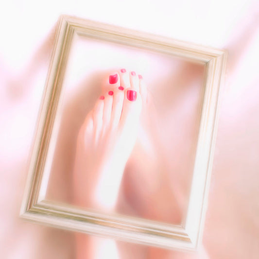 A photo of feet with red painted nails, with a photo frame resting on top. 