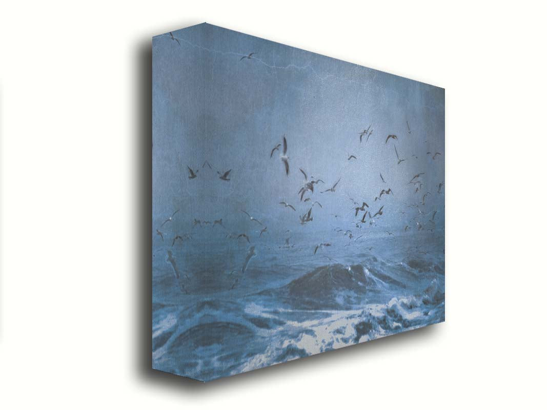 An edited photo of a flock of seagulls swarming over the sea in search of food, as the sky darkens and the waves pick up with an oncoming storm. Printed on canvas.