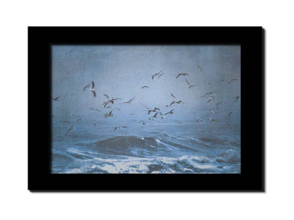 An edited photo of a flock of seagulls swarming over the sea in search of food, as the sky darkens and the waves pick up with an oncoming storm. Printed on canvas and framed.