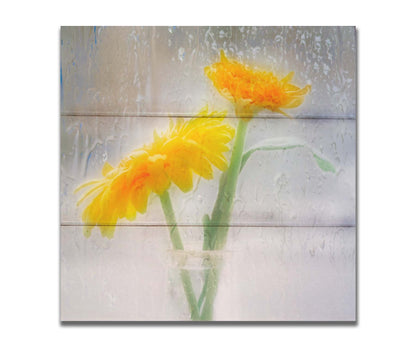 A photo of two yellow flowers in a small glass jar in soft light, edited as viewed through wet glass. Printed on a box board.