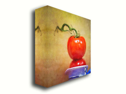 A photograph of bright red tomatoes stacked inside a blue and white ceramic cup, set against a textured neutral background. Printed on canvas.