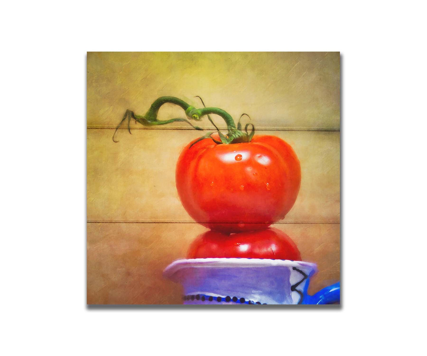 A photograph of bright red tomatoes stacked inside a blue and white ceramic cup, set against a textured neutral background. Printed on a box board.