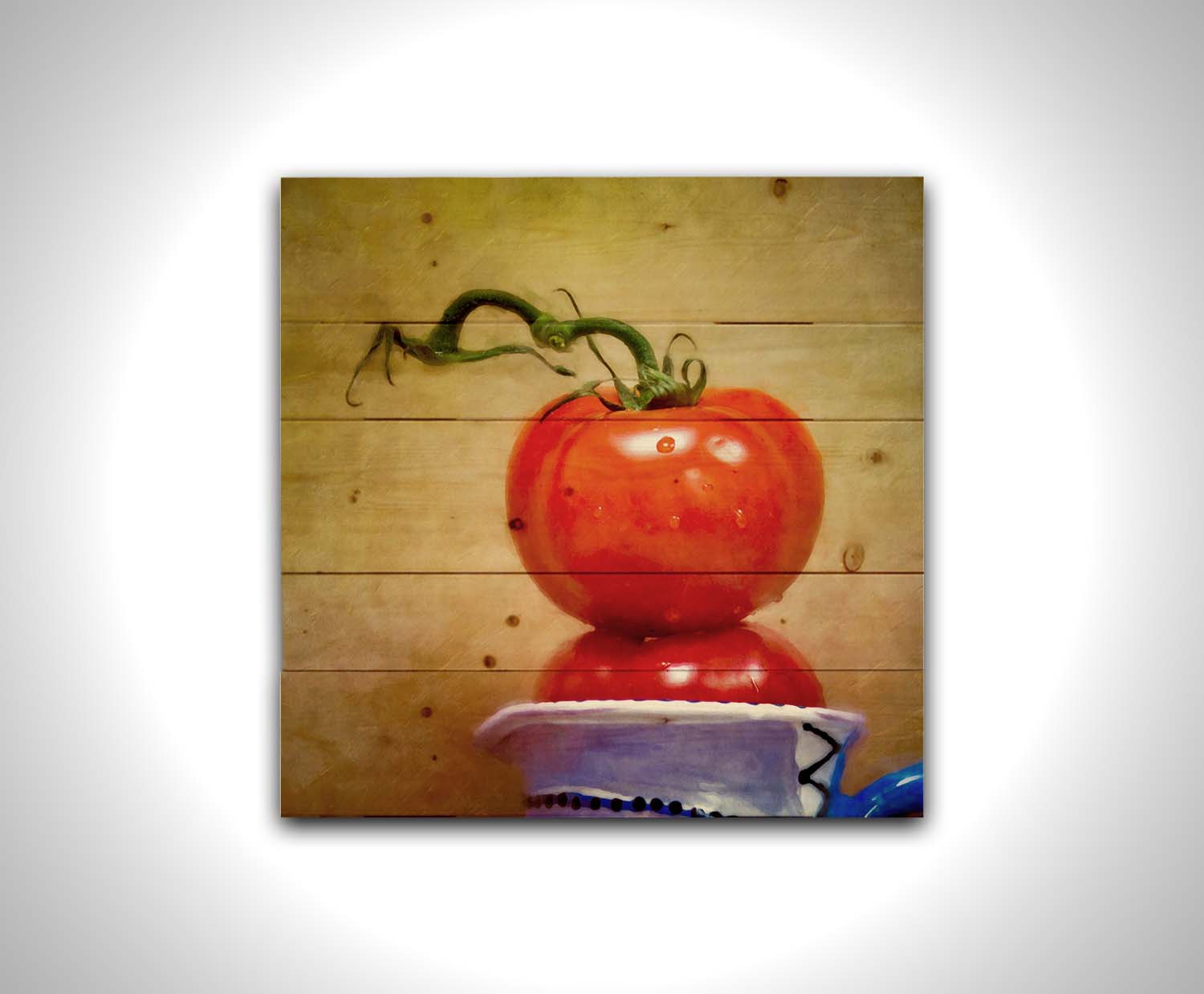 A photograph of bright red tomatoes stacked inside a blue and white ceramic cup, set against a textured neutral background. Printed on a wood pallet.