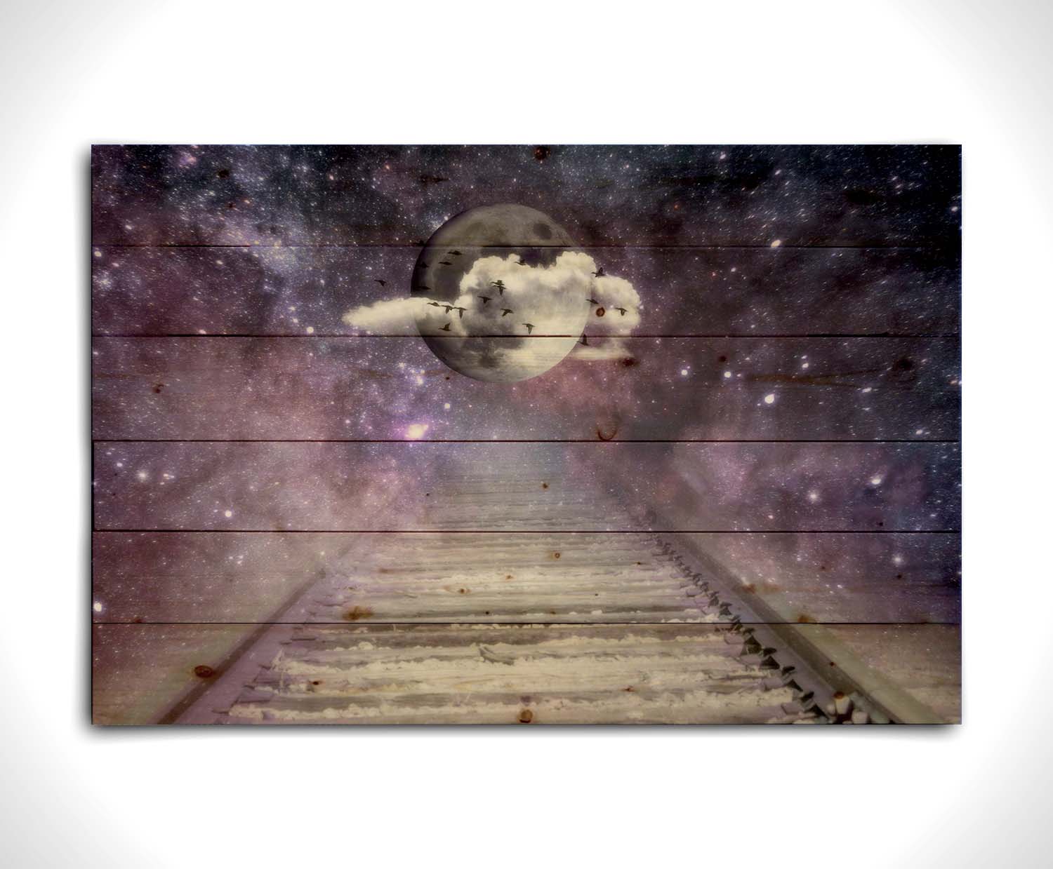 An edited photo looking down train tracks, leading into a starry space view. In the center is a moon surrounded by wispy clouds, with silhouetted geese flying across it. Printed on a wood pallet.