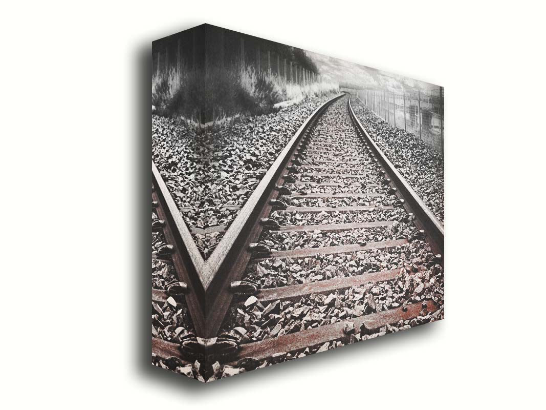 A photo looking down train tracks in black and white, with tinges of red-brown spot color. Printed on canvas.