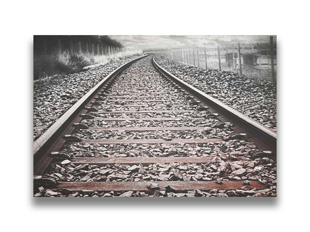 A photo looking down train tracks in black and white, with tinges of red-brown spot color. Printed on canvas.