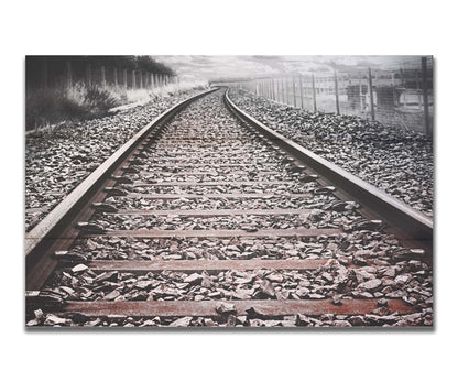 A photo looking down train tracks in black and white, with tinges of red-brown spot color. Printed on a box board.