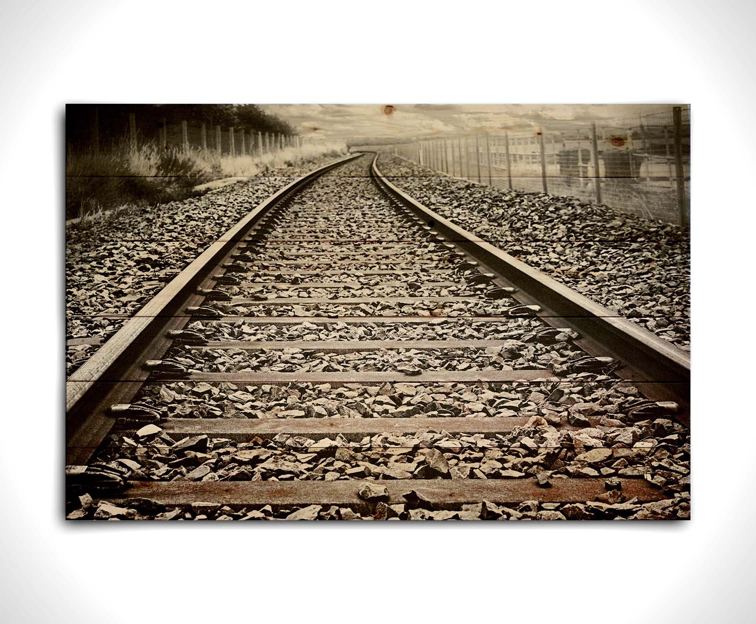 A photo looking down train tracks in black and white, with tinges of red-brown spot color. Printed on a wood pallet.