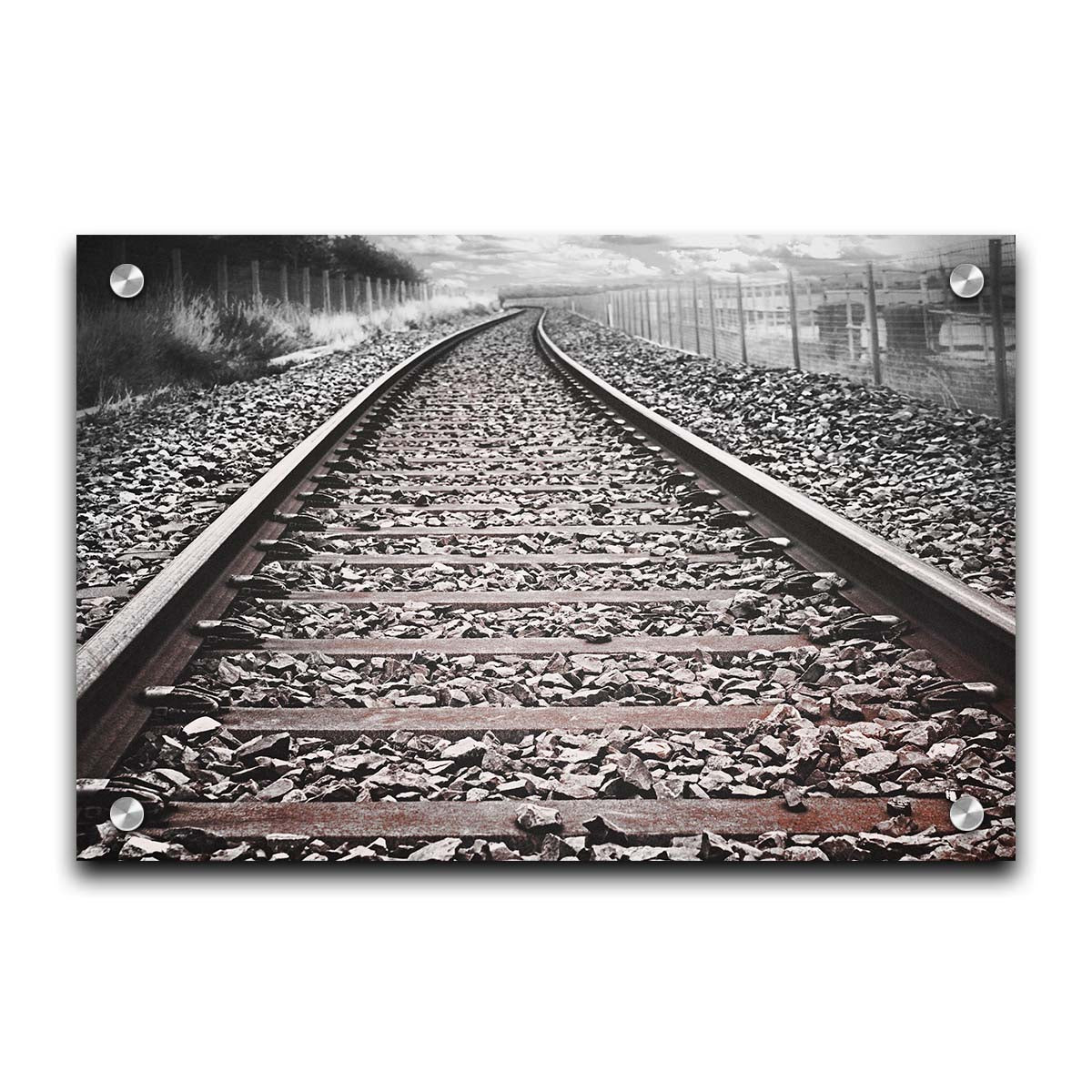 A photo looking down train tracks in black and white, with tinges of red-brown spot color. Printed on acrylic.