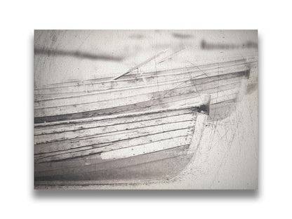 A grayscale photo of two rowboats on the sand. It is overlayed with a scratchy weathered texture. Printed on canvas.