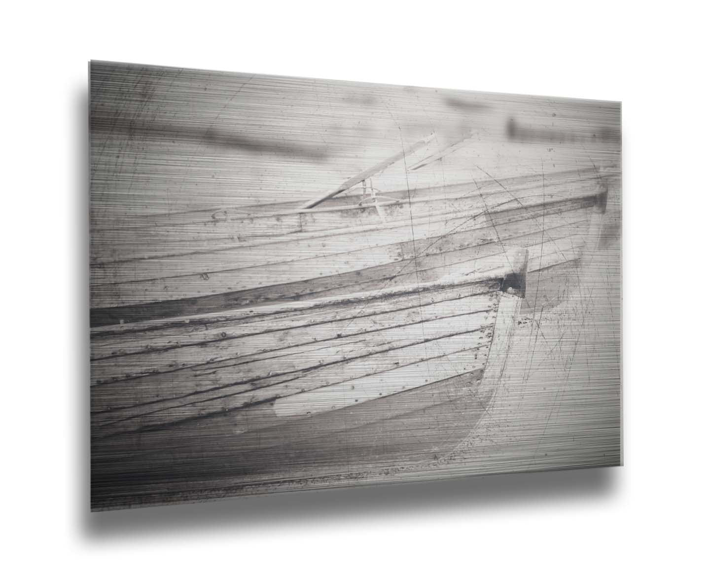 A grayscale photo of two rowboats on the sand. It is overlayed with a scratchy weathered texture. Printed on metal.