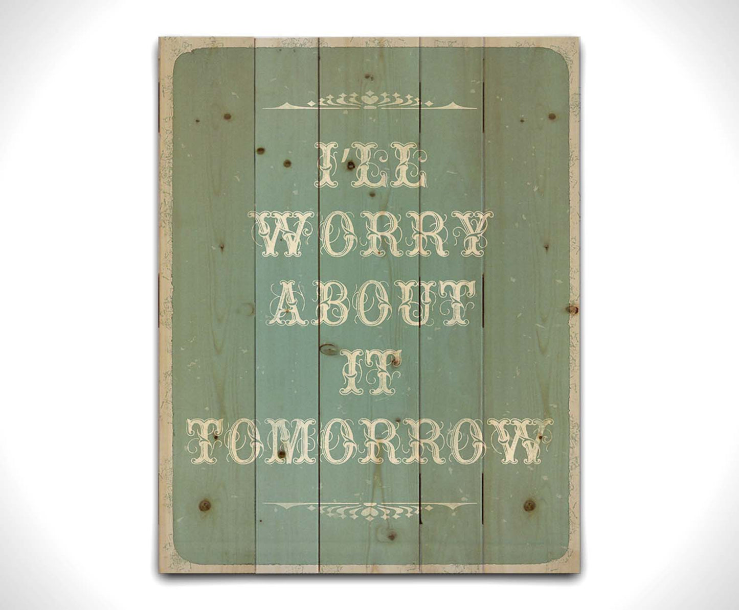 A typography design reading "I'll worry about it tomorrow" in white on a pale blue background. Printed on a wood palelt.