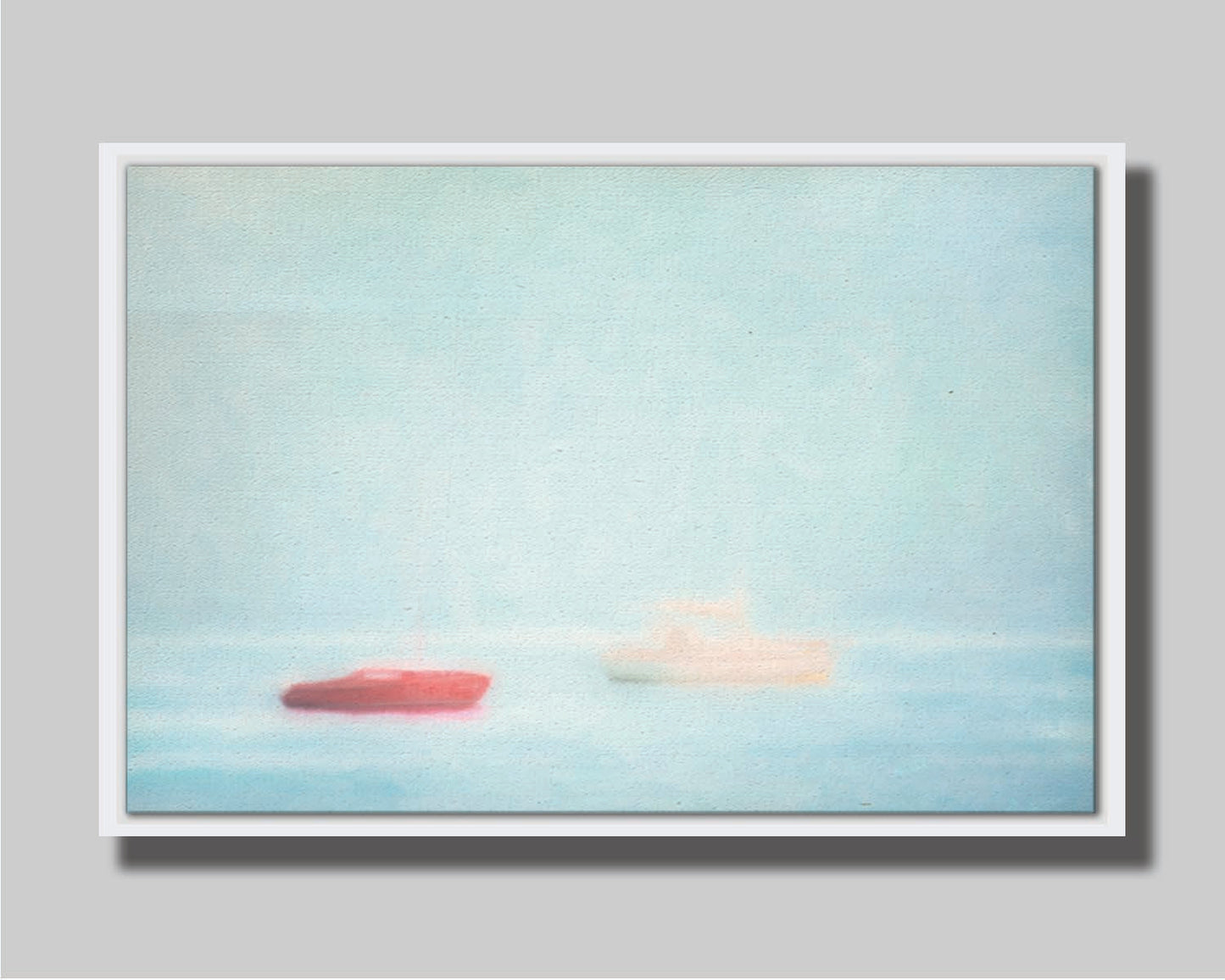 A photo of a small red boat and a small white and yellow boat floating at sea. The photo is edited to have a soft, blurry quality which blends the sky and sea together on the horizon. Printed on canvas in a float frame.