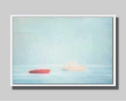 A photo of a small red boat and a small white and yellow boat floating at sea. The photo is edited to have a soft, blurry quality which blends the sky and sea together on the horizon. Printed on canvas in a float frame.