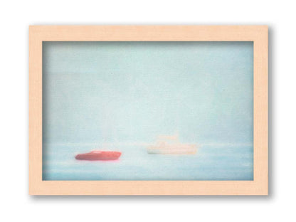 A photo of a small red boat and a small white and yellow boat floating at sea. The photo is edited to have a soft, blurry quality which blends the sky and sea together on the horizon. Printed on canvas and framed.