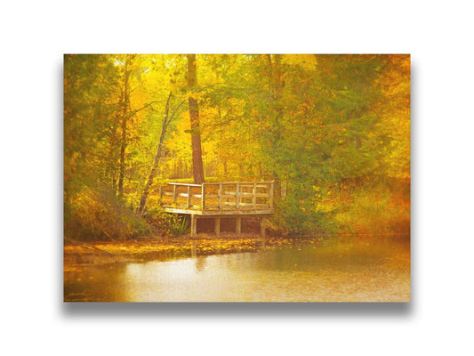 A photo of a small wooden dock, overlooking a forest lake during autumn. Yellow leaves cover the trees and ground, and float atop the water. Printed on canvas.