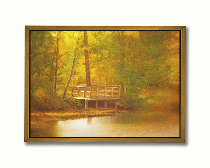 A photo of a small wooden dock, overlooking a forest lake during autumn. Yellow leaves cover the trees and ground, and float atop the water. Printed on canvas in a float frame.