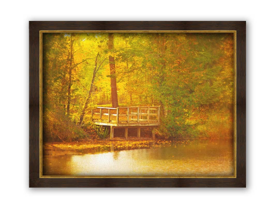 A photo of a small wooden dock, overlooking a forest lake during autumn. Yellow leaves cover the trees and ground, and float atop the water. Printed on canvas and framed.