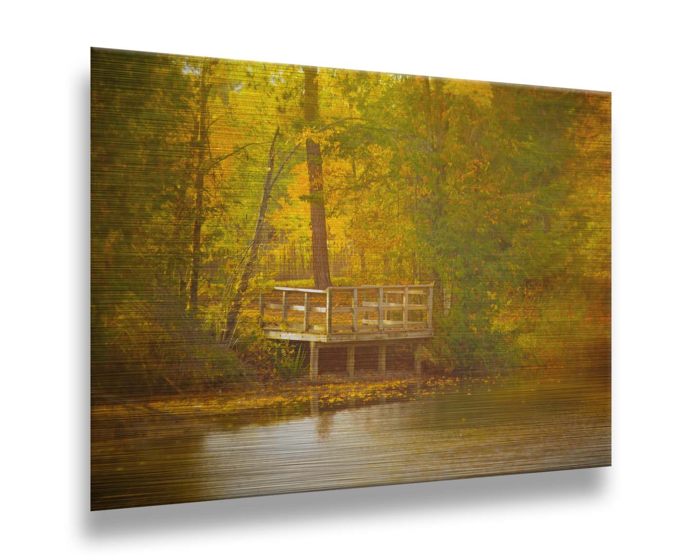 A photo of a small wooden dock, overlooking a forest lake during autumn. Yellow leaves cover the trees and ground, and float atop the water. Printed on metal.