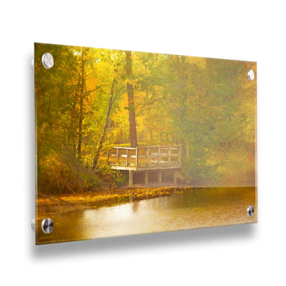 A photo of a small wooden dock, overlooking a forest lake during autumn. Yellow leaves cover the trees and ground, and float atop the water. Printed on acrylic.