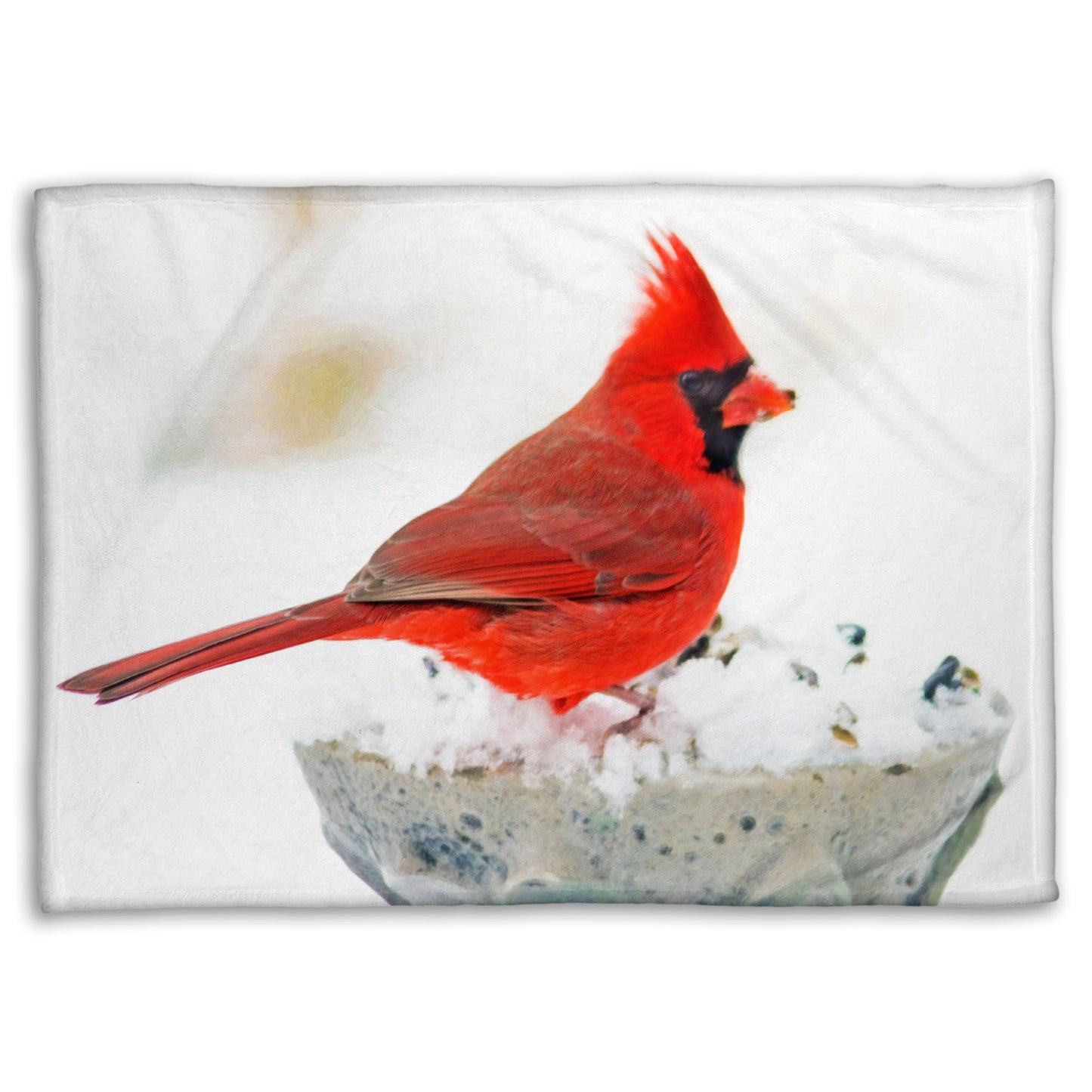 A coral fleece blanket printed with a photograph of a red cardinal against white snow.