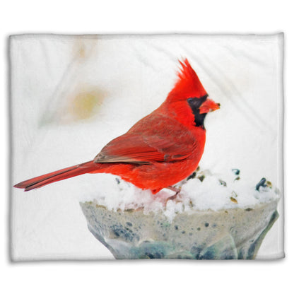 A coral fleece blanket printed with a photograph of a red cardinal against white snow.