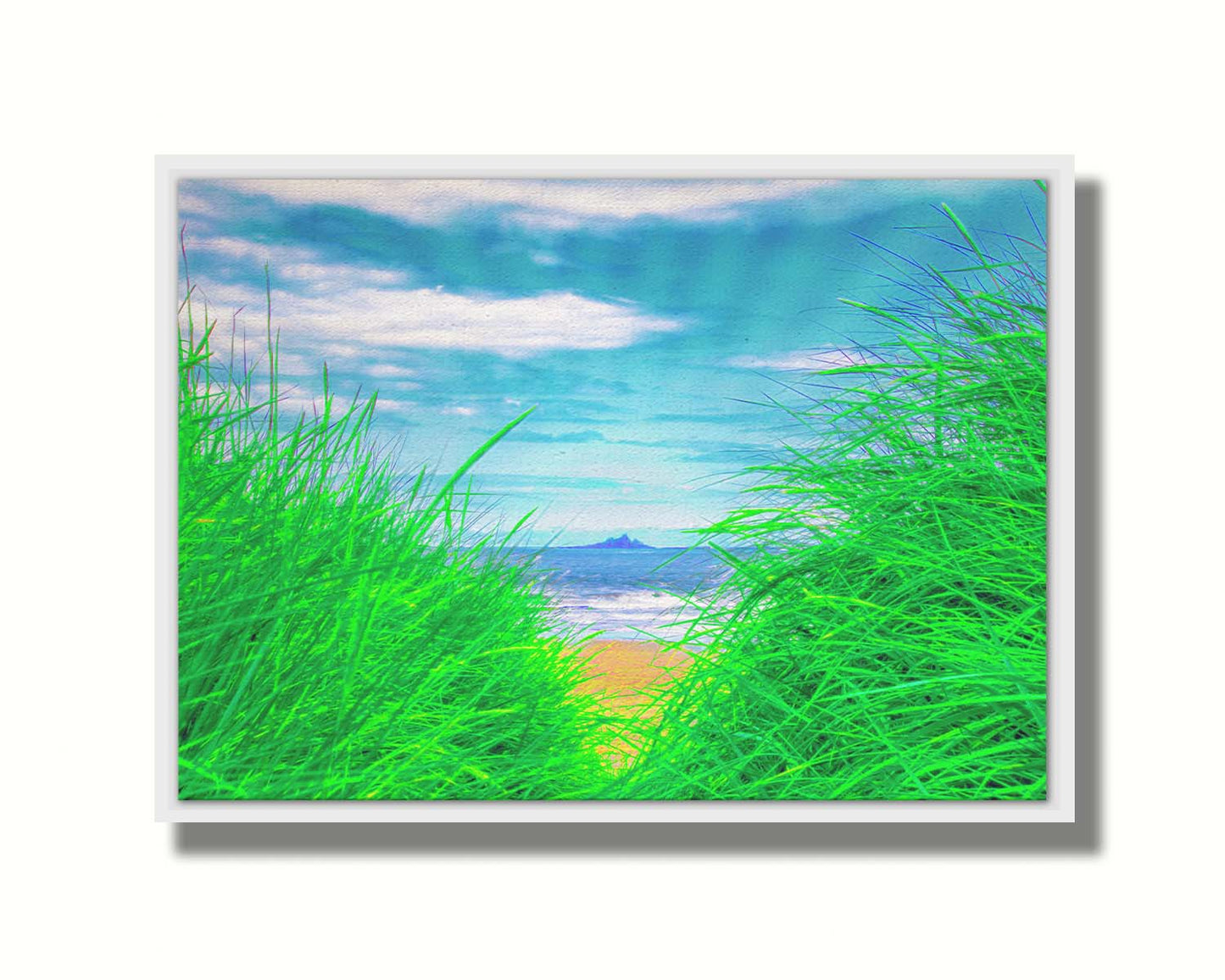 A photograph, edited to increase saturation, looking out at the sea between grassy plants on the beach. A rocky outcropping can be seen in the distance. Printed on canvas in a float frame.