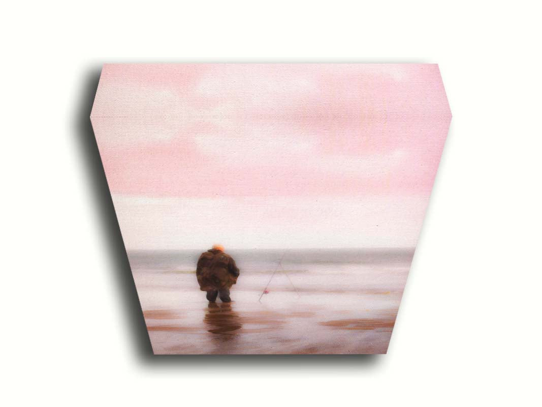 A photograph of a fisherman in oilskins standing in the shallows of the ocean, watching his fishing pole propped up beside him. Printed on canvas.