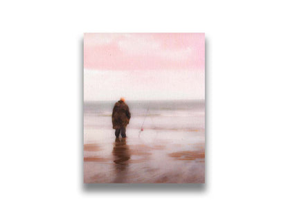 A photograph of a fisherman in oilskins standing in the shallows of the ocean, watching his fishing pole propped up beside him. Printed on canvas.