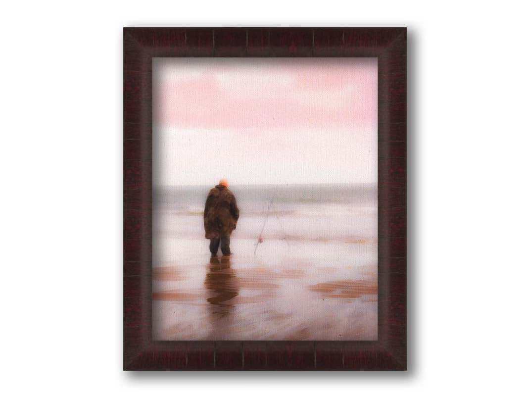 A photograph of a fisherman in oilskins standing in the shallows of the ocean, watching his fishing pole propped up beside him. Printed on canvas and framed.