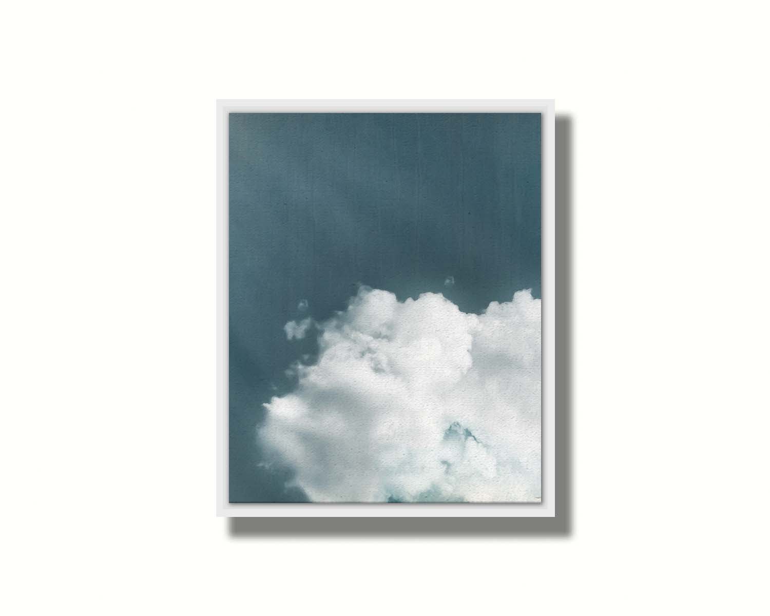 An edited photo of a soft white cloud against a steely blue background. Printed on canvas in a float frame.