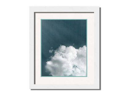 An edited photo of a soft white cloud against a steely blue background. Printed on paper, matted, and framed.