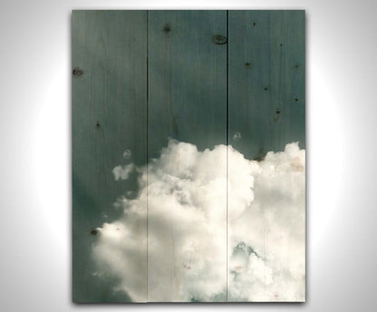 An edited photo of a soft white cloud against a steely blue background. Printed on a wood pallet.