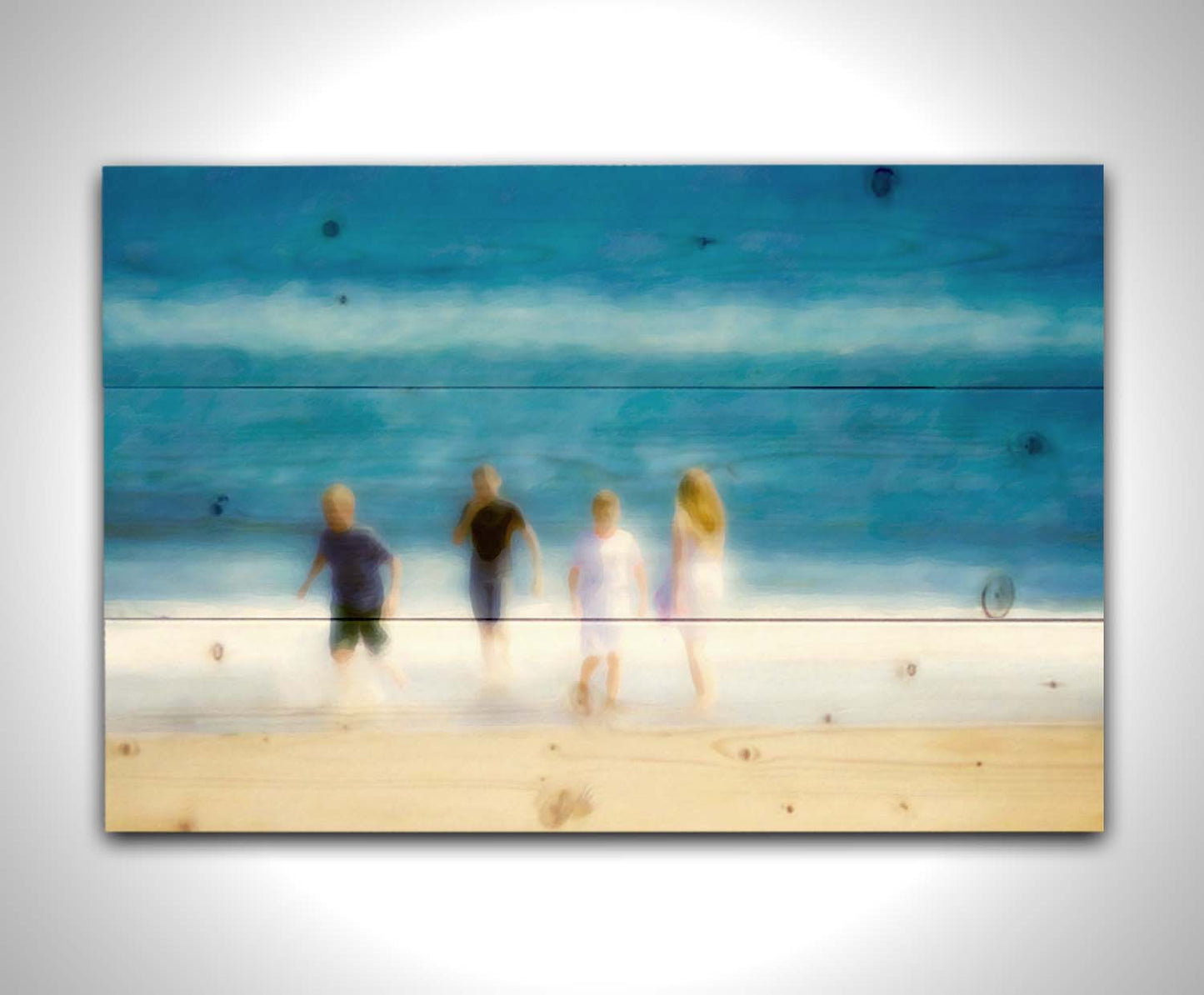 A photograph of four children walking on the beach by the water's edge. It is edited with an effect that gives it a painterly, dreamlike quality. Printed on a wood pallet.