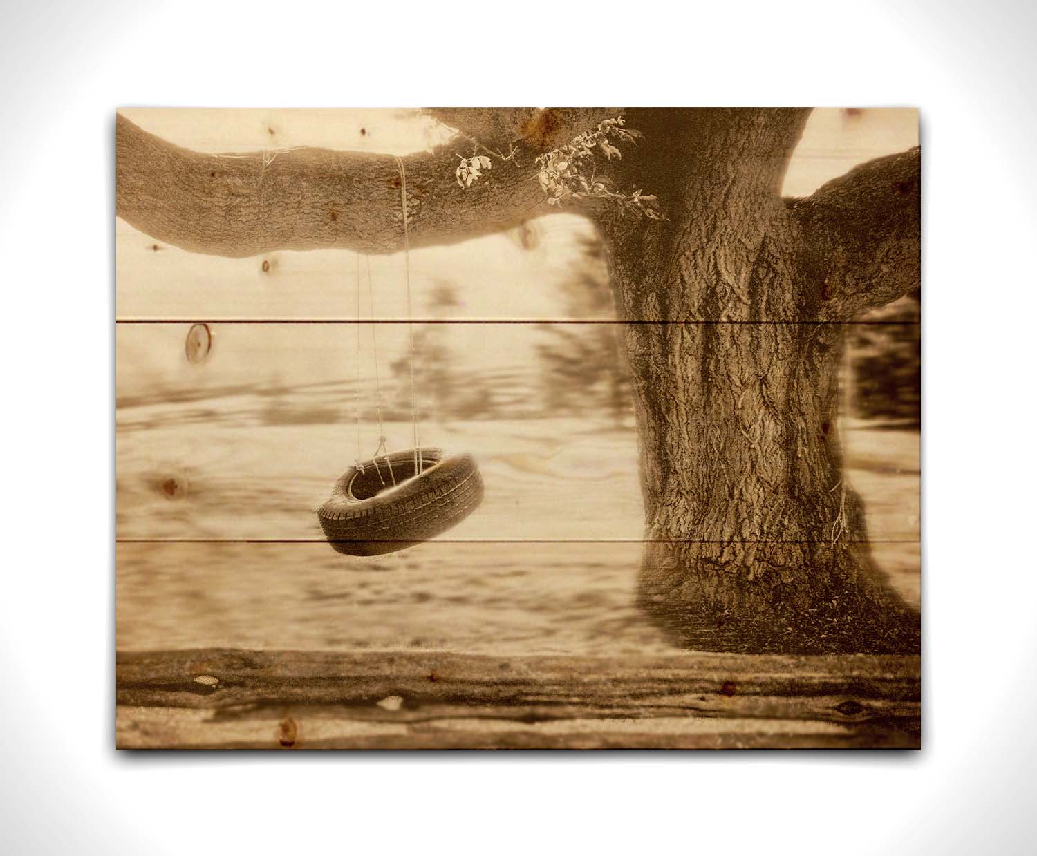 A sepia-tone photograph of a tire swing hanging from a sturdy tree in the daylight. Printed on a wood pallet.