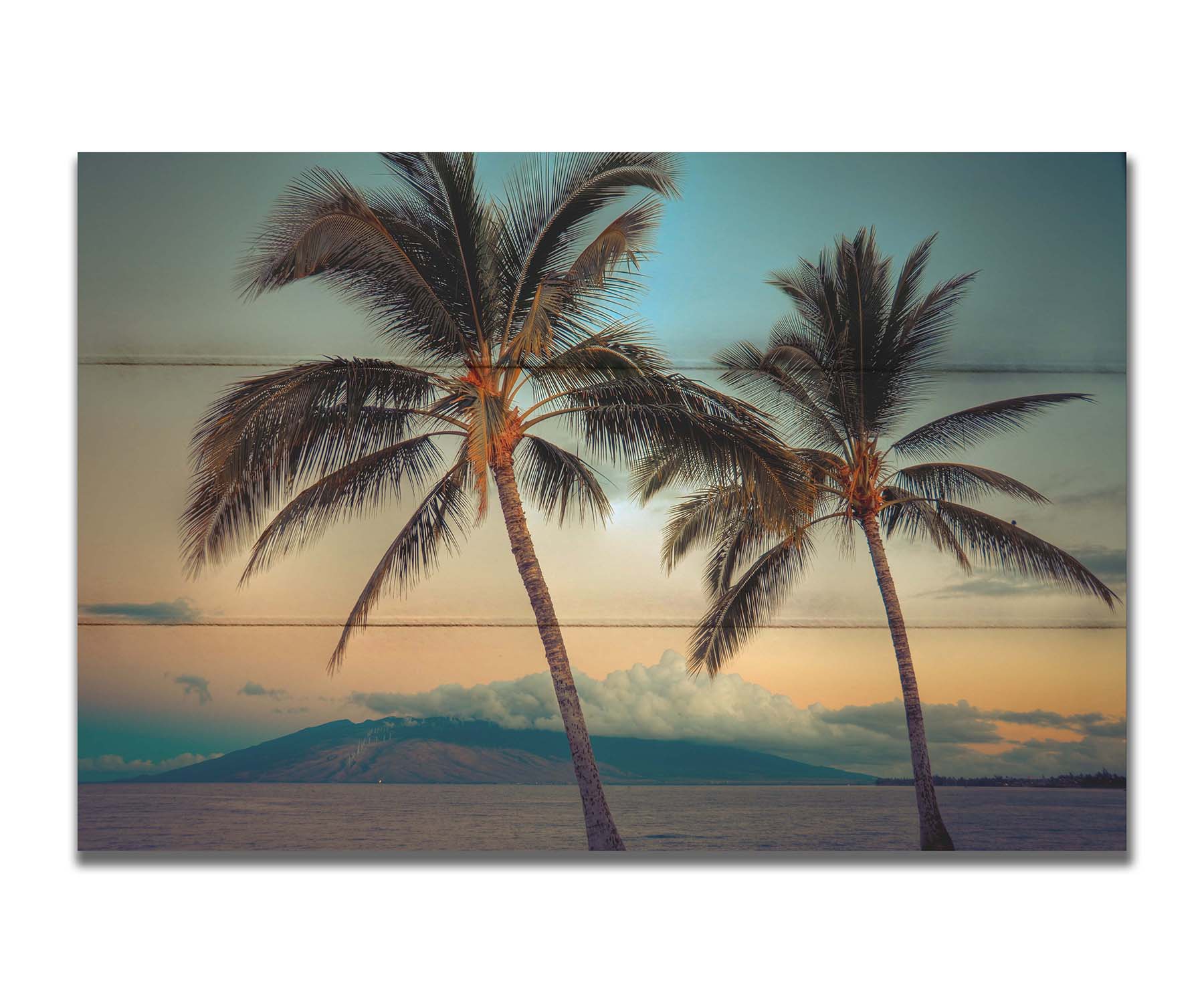 A photo of two palm trees in Maui at sunset, with the sea and cloud-topped mountains in the background. Printed on a box board.