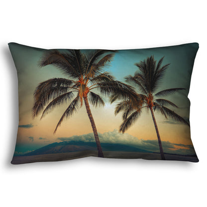 A throw pillow designed with a photo of two palm trees in Maui at sunset, with the sea and cloud-topped mountains in the background.