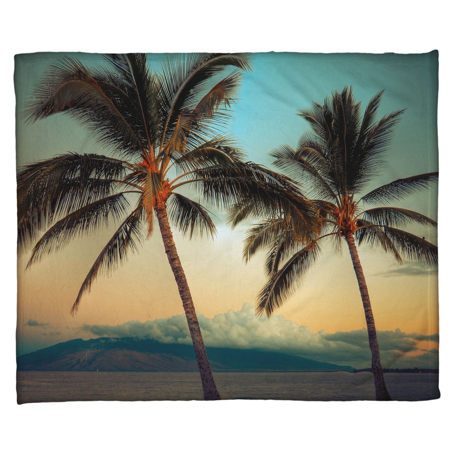 A coral fleece throw blanket designed with a photo of two palm trees in Maui at sunset, with the sea and cloud-topped mountains in the background.