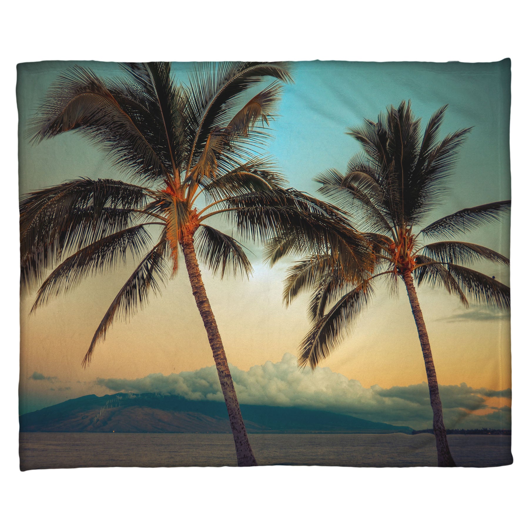 A coral fleece throw blanket designed with a photo of two palm trees in Maui at sunset, with the sea and cloud-topped mountains in the background.