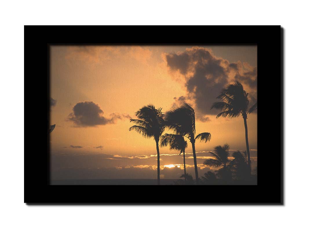 A photo of palm trees in Maui silhouetted by the setting sun, with the sea in the background. Printed on canvas and framed.