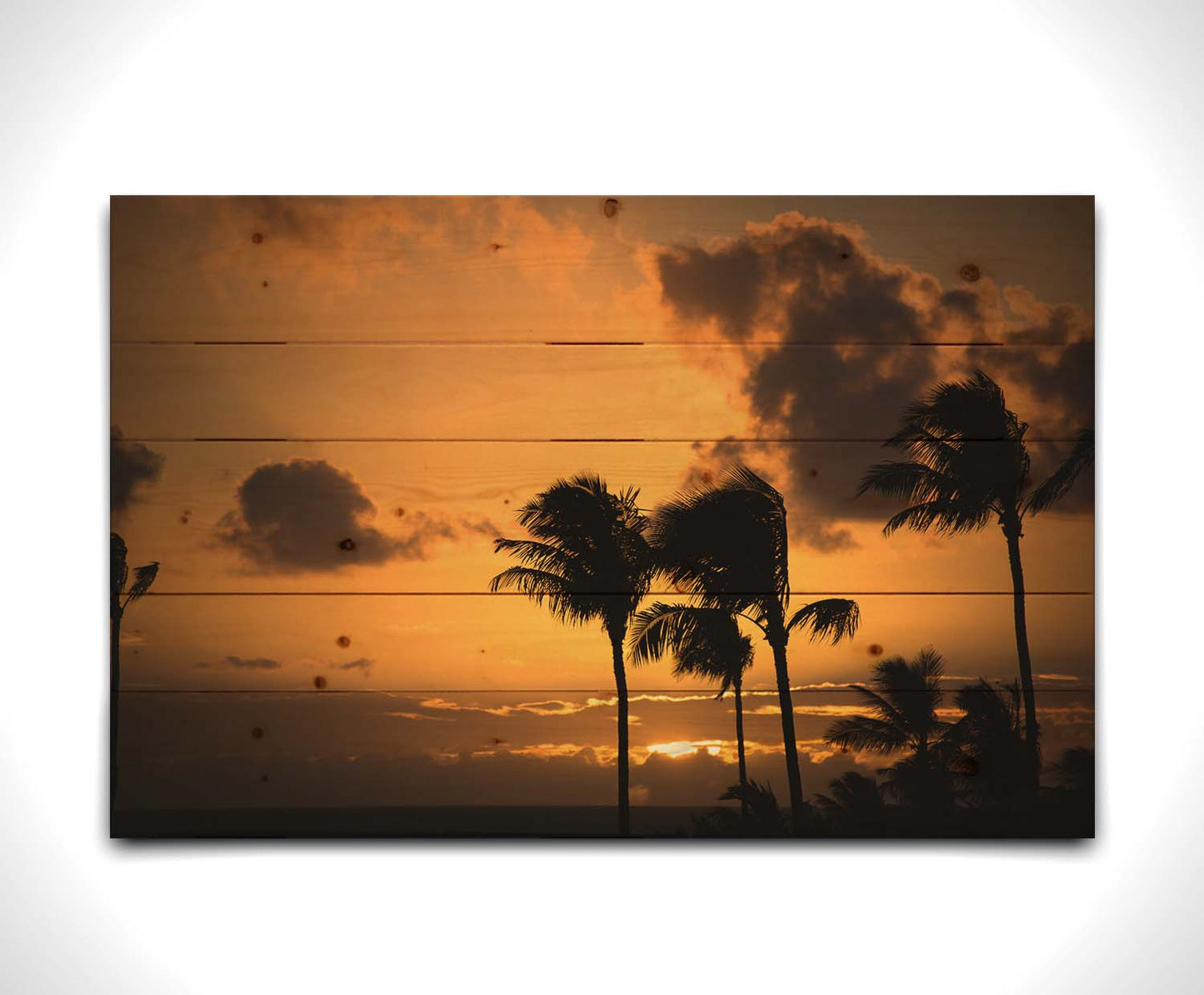 A photo of palm trees in Maui silhouetted by the setting sun, with the sea in the background. Printed on a wood pallet.