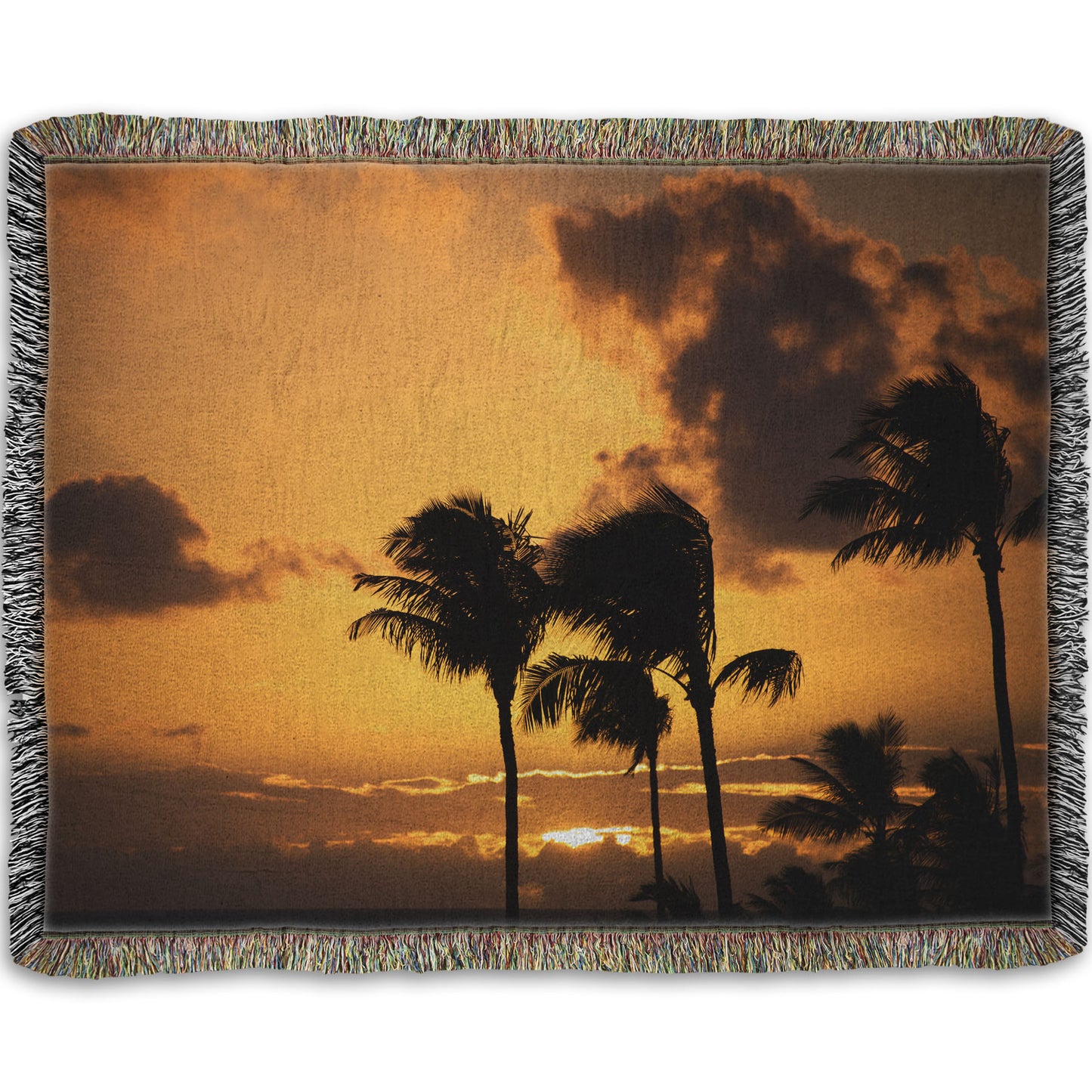 A woven throw blanket designed with a photo of palm trees in Maui silhouetted by the setting sun, with the sea in the background.