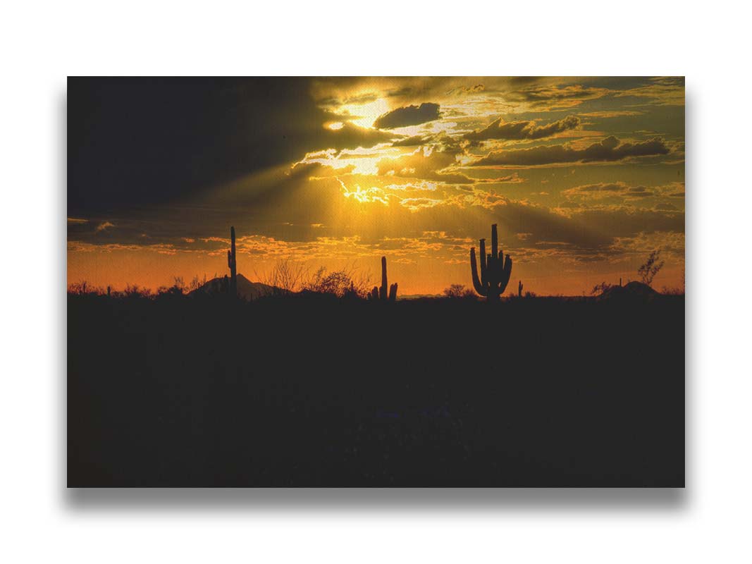 A photo of a sunset over the desert in Arizona, the landscape shadowed in black against the orange and yellow sky. Printed on canvas.