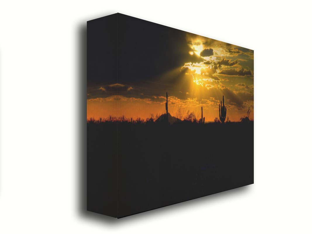 A photo of a sunset over the desert in Arizona, the landscape shadowed in black against the orange and yellow sky. Printed on canvas.