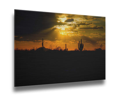 A photo of a sunset over the desert in Arizona, the landscape shadowed in black against the orange and yellow sky. Printed on metal.