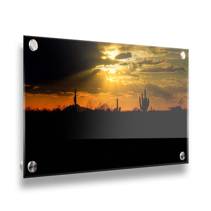 A photo of a sunset over the desert in Arizona, the landscape shadowed in black against the orange and yellow sky. Printed on acrylic.