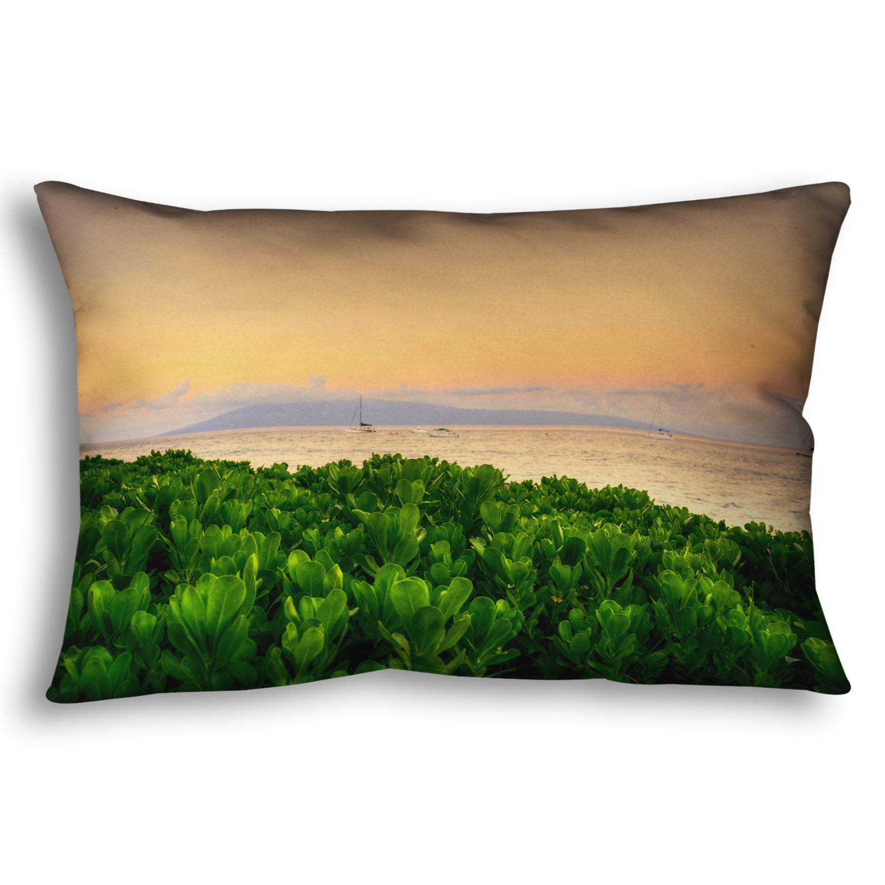 A throw pillow designed with a photo overlooking the sea from Kaanapali beach in Hawaii. Green plants fill the foreground, and boats sail on the water in the distance against a gentle orange sky and purple clouds. 