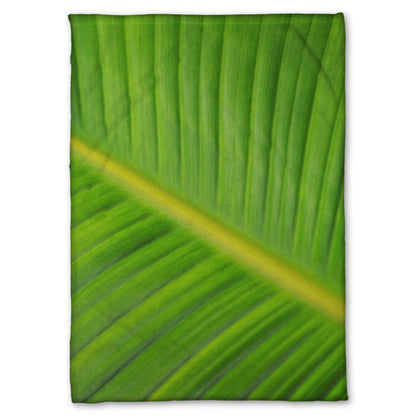 A fleece throw blanket designed with a closeup photo of a leaf of a bird of paradise palm, showing all the detail of the midrib and veins of the leaf.